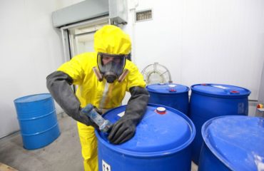 A food chemical safety image of a worker opening a big blue container.
