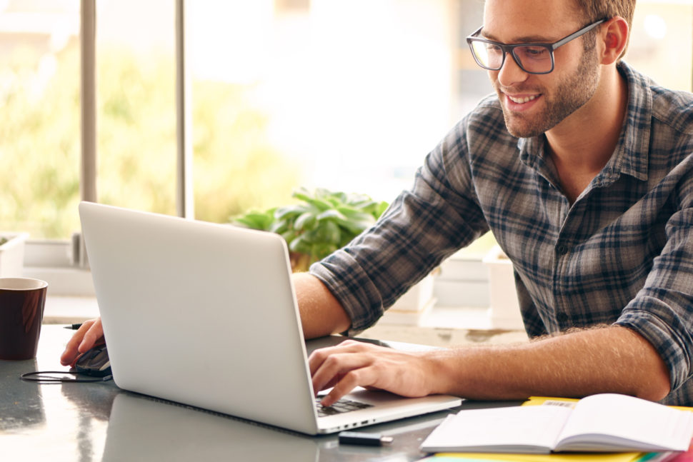 Young man smiles and works from home