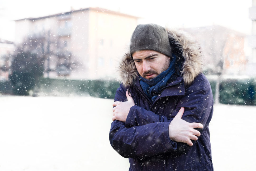 A man shivers in snowy conditions