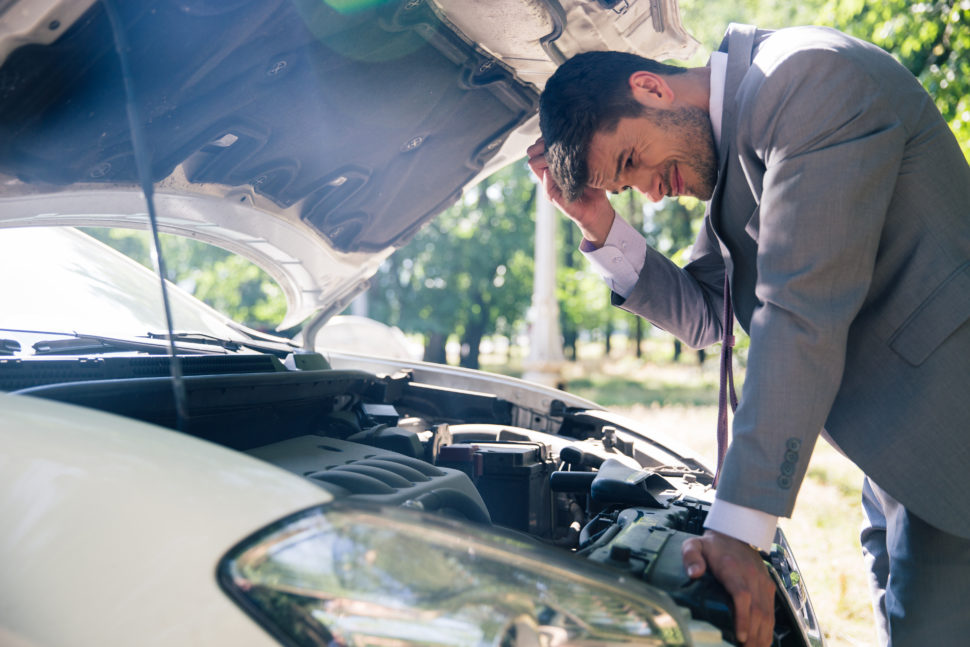 man looking under hood of car